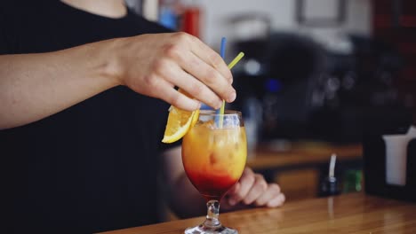 tasty cocktail in glass. bartender cooks the beverage for client. fresh alcohol drink ready on a bar table. slice of orange on a glass with color liquid with ice.