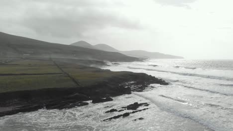 aerial of rising drone above rugged irish coastline with waves and white spray