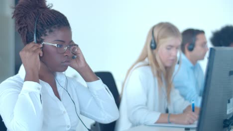 operador de centro de llamadas afroamericano enfocado que se pone los auriculares