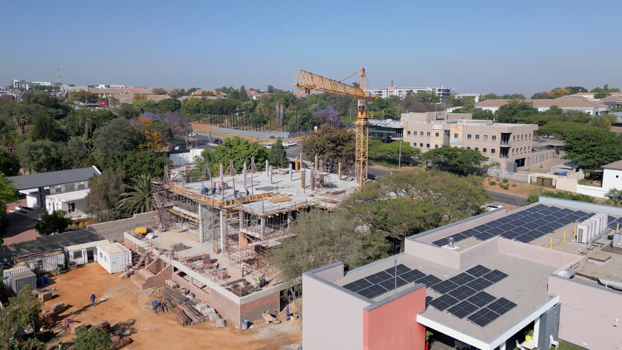 A construction crew and crane building an office structure