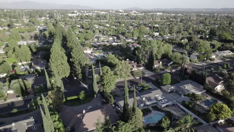 older homes in northridge suburb neighborhood, surrounded by trees, aerial on clear afternoon