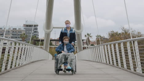 mother walking with son in wheelchair