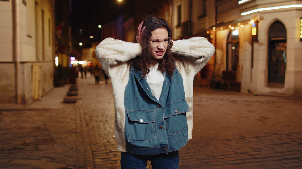 Displeased angry girl frowns face feels disgust suffering from loud sound covers ears with hands