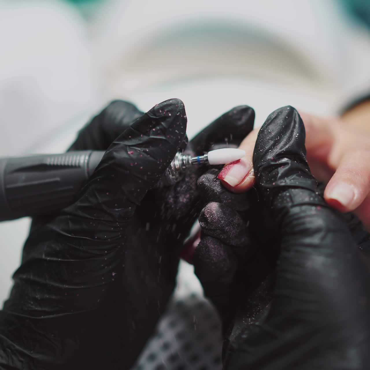 master of manicure is holding the client's hand and removing the gel polish by professional equipment in the beauty salon