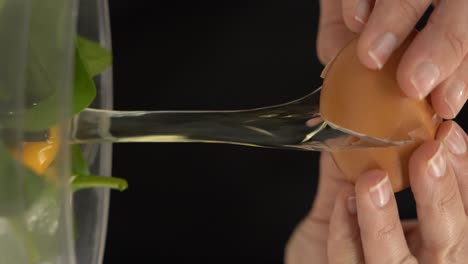 Vertical video of cracking an egg over a bowl
