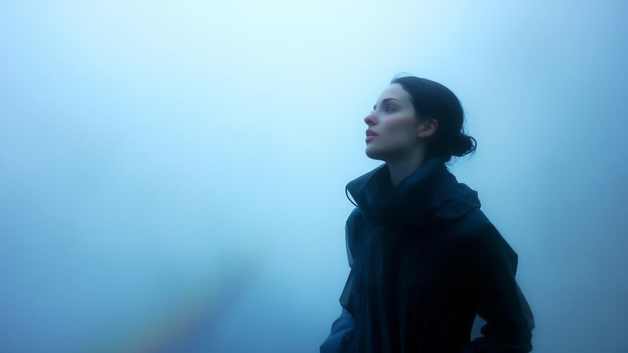 A solitary figure stands in an ethereal landscape, enveloped by a haze of blue fog, evoking a sense of introspection and tranquility as they gaze into the unseen distance