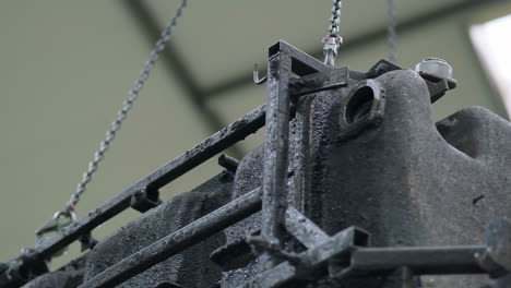 load of steal and plastic structure is carrying by a hoist on a sliding rail, inside an industrial hall, narrow shot from the ground