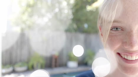 animación de puntos de luz sobre la mitad retrato de una adolescente caucásica feliz sonriendo en el jardín
