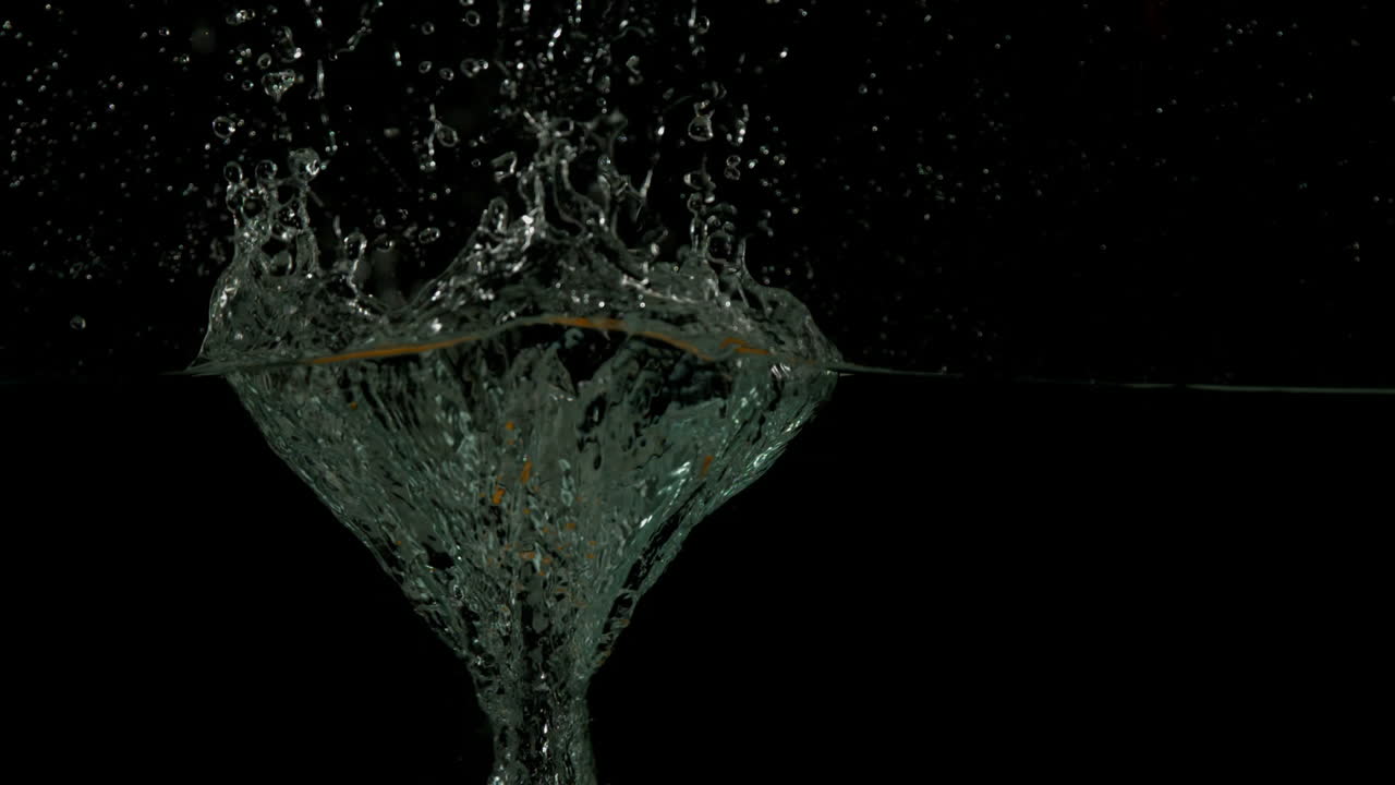 Apple plunging into water on black background