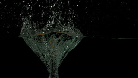 manzana sumergiéndose en el agua sobre un fondo negro