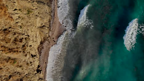 ocean waves splashing and foaming on rocky coastline, sea scenery with brown turquoise colors