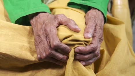 las manos de los ancianos en las rodillas