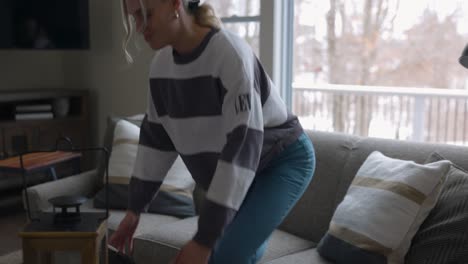 woman walking to the couch to lay down and scroll through tablet while drinking coffee in a nice house