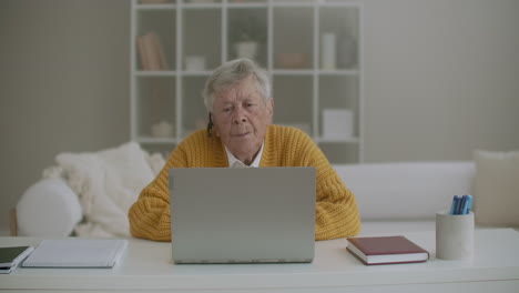 Una-Mujer-Mayor-Con-Pelo-Gris-Hace-Videollamadas-Usando-Una-Computadora-Portátil-En-Casa.-Anciana-Haciendo-Una-Videollamada-Con-Su-Familia-Sonriendo-Y-Saludando.-Covid-19-Mantente-Conectado.-Chateando-En-Línea-Con-Amigos