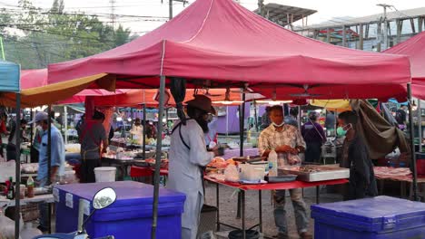 vendedores y compradores interactúan en un mercado concurrido.