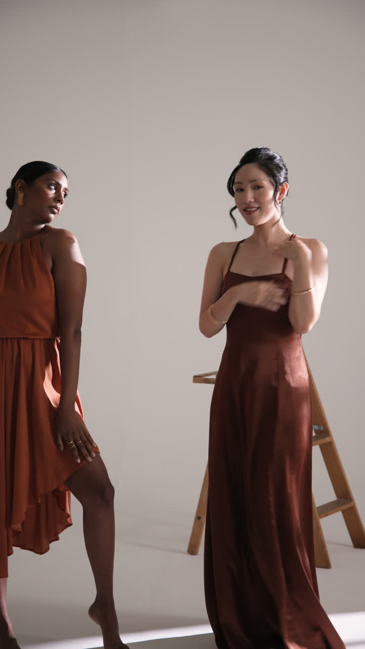 Vertical video: Models in elegant dresses posing confidently in fashion studio setting