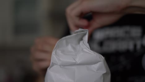 Close-up-of-young-caucasian-male-hands-opening-sealed-paper-bag