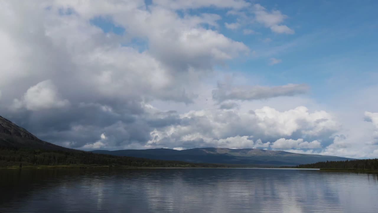 배경에 산이 있고 폭풍과 함께 구름이 움직이는 조용한 호수의 시간 경과