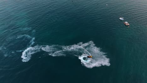 a jet ski creates a splash in the calm waters of ksamil, albania, during a peaceful sunset