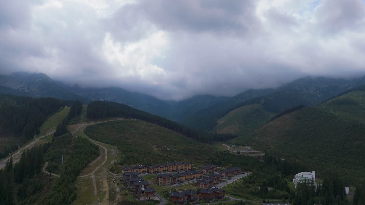 Aerial footage of Demanovska Dolina in Slovakia, showing Jasna ski resort, Vrbicke pleso lake, mountain peaks, and drifting clouds. Beautiful nature and travel visuals from the Zilina region