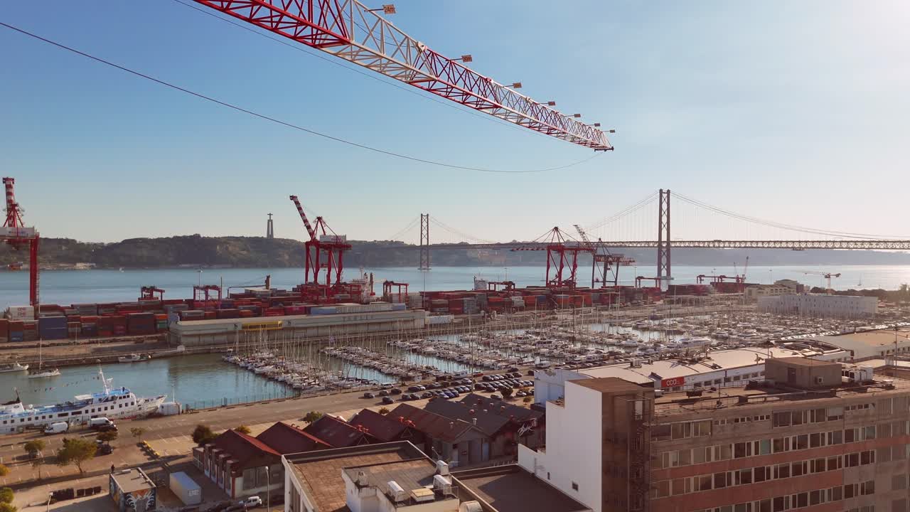 Aerial view of a busy cargo port in Lisbon with cranes and a bridge