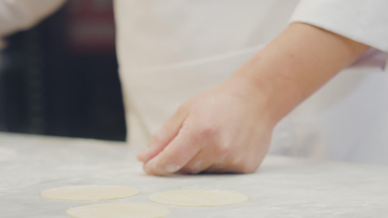Chef's hands shaping and cutting the ravioli dough using artisanal techniques in a professional kitchen