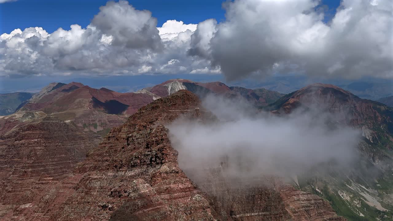North Maroon Peak fog dissipating Aspen Snowmass Maroon Bells Wilderness valley Colorado summer panoramic view fourteener Elk Range Rocky Mountains rugged terrain sunny blue sky clouds static shot