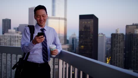 asian businessman using touchscreen on rooftop at sunrise