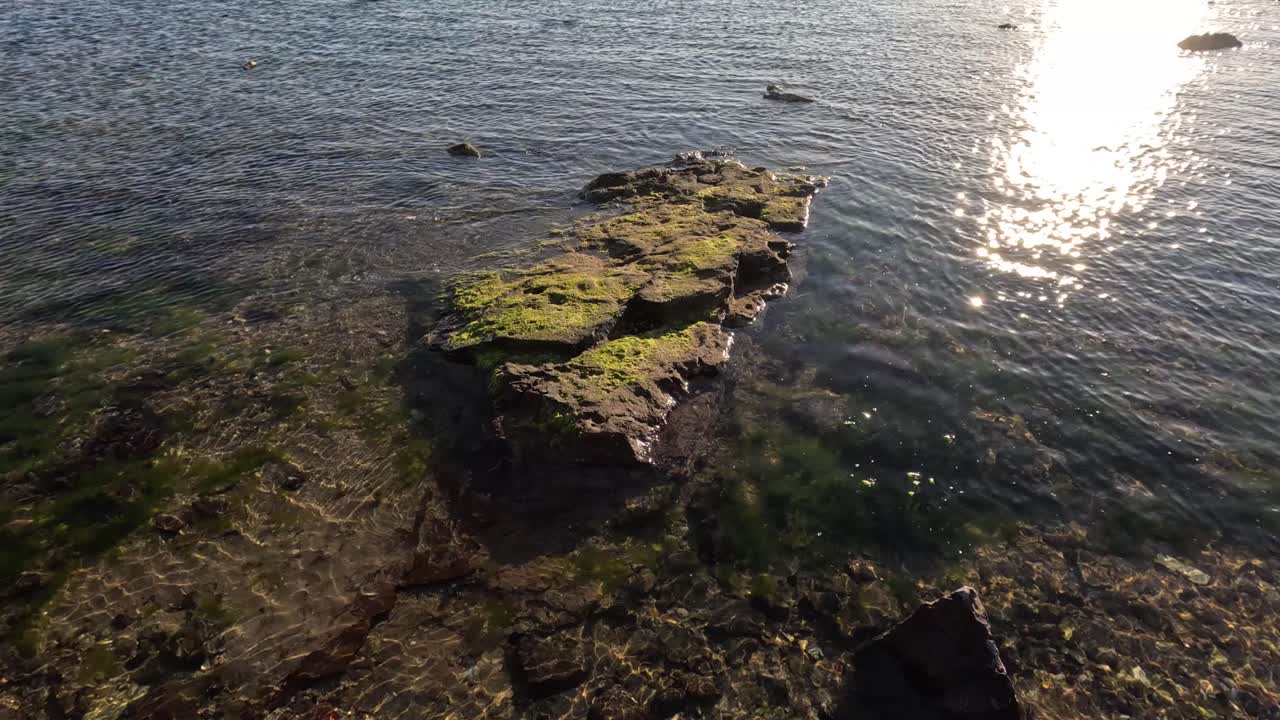 해가 뜨면 바위와 평온한 바다의 물이 빛납니다.