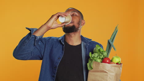 young adult enjoying a cup of coffee during his grocery shopping spree