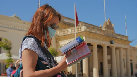 young female traveler on vacation in valletta malta outside the grandmasters palace checking her guide book for references