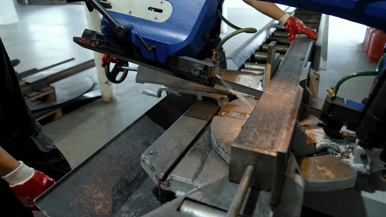 Industrial machine with a band saw cuts a metal pipe. Supply of coolant emulsion