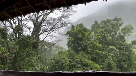 Fuertes-Lluvias-Vistas-Desde-El-Balcón-Del-Hotel-Lodge-Con-Vegetación-Tropical-Durante-El-Monzón-Con-La-Montaña-Al-Fondo-Vista-A-Través-De-La-Niebla