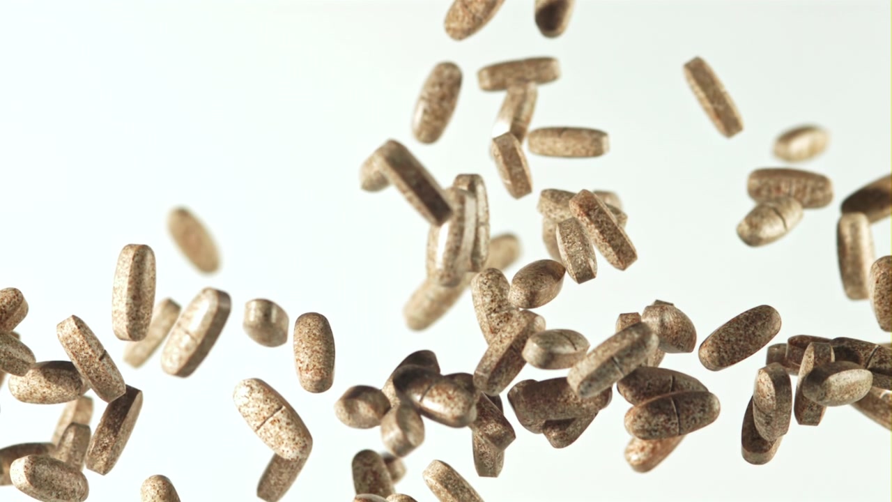 Brown Pills and Tablets Falling in Slow Motion Against a White Background
