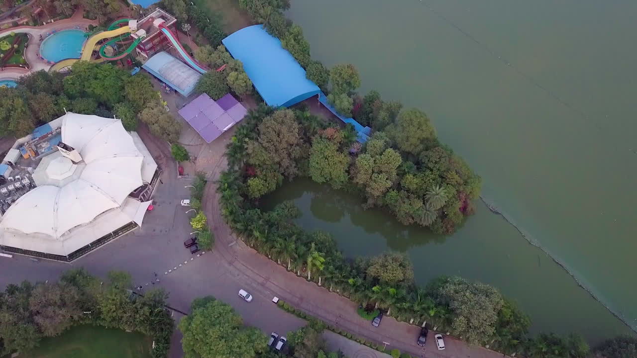 Aerial view capturing a resort situated beside a lake in Hyderabad, India during sunset.