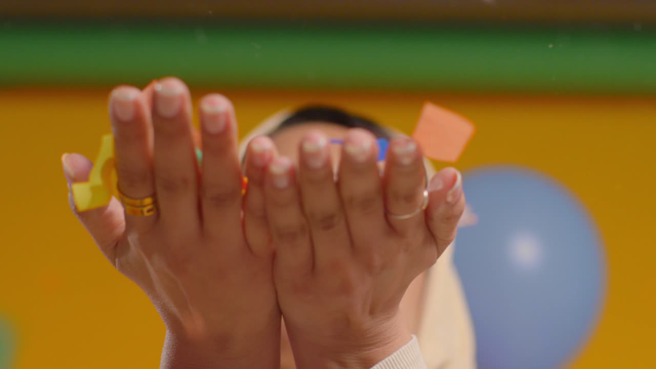 히자브를 입은 여성이 생일파티를 축하하고 종이 파티 콘페티를 불어넣는 클로즈업