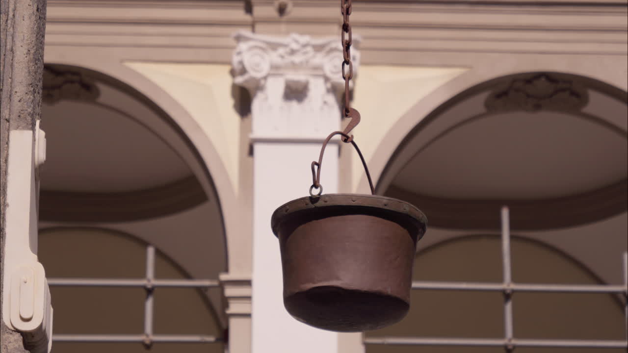 Vaso di metallo rustico antico appeso di fronte a un edificio storico ad arco