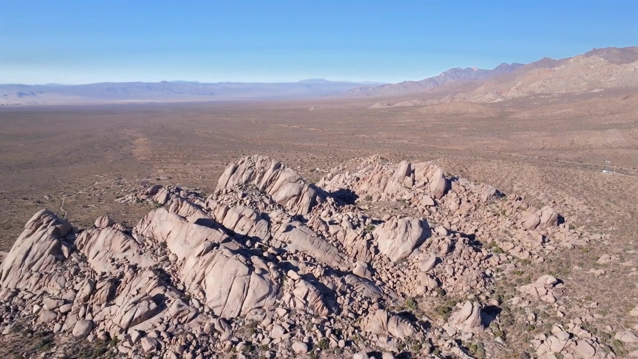Dune di Kelso Pinto Basin, Parco Nazionale di Joshua Tree, California, ripresa aerea con drone, alberi di Yucca, Contea di San Fernando, deserto del Mojave e del Colorado, cielo blu, collina aspra, formazione rocciosa, pomeriggio soleggiato, discesa circolare a destra.