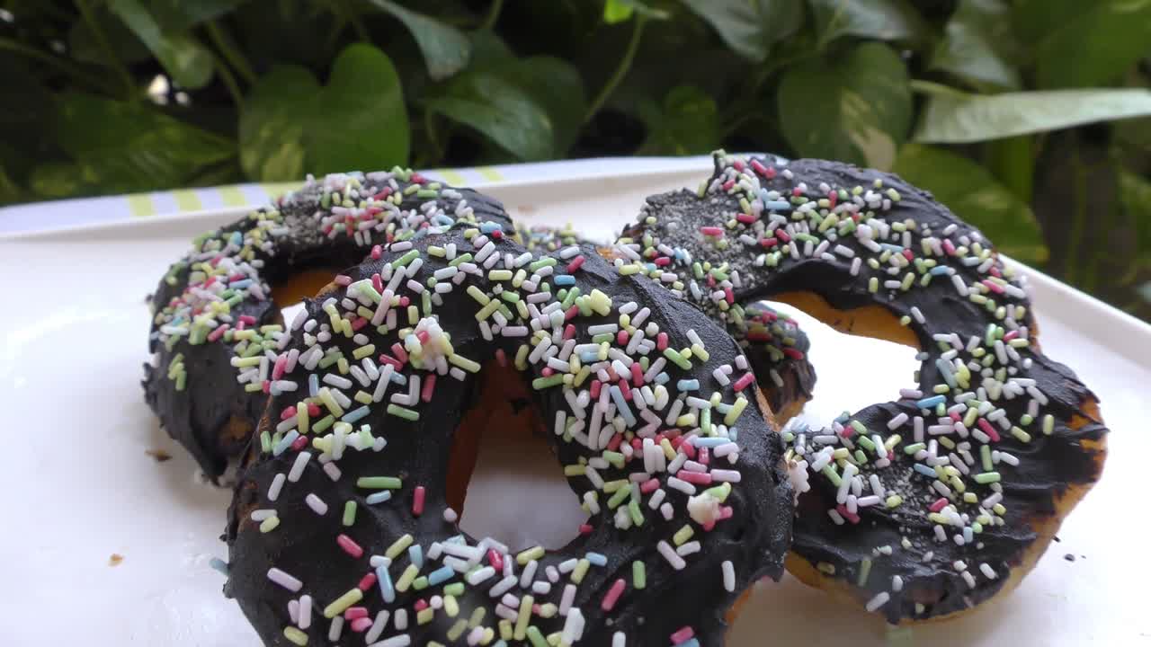 Dark chocolate doughnuts in plate on the covered table
