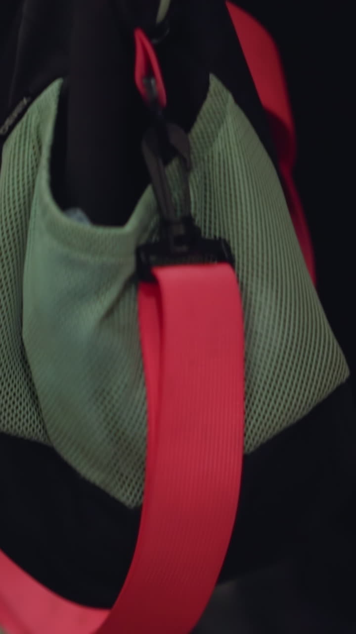 Close-up view of a backpack or gym bag with a prominent red strap, positioned on an escalator step. and the metal ridges of the escalator