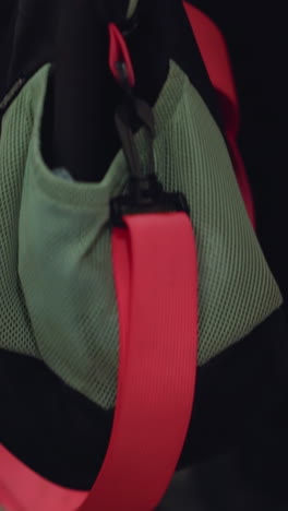 close-up view of a backpack or gym bag with a prominent red strap, positioned on an escalator step. and the metal ridges of the escalator