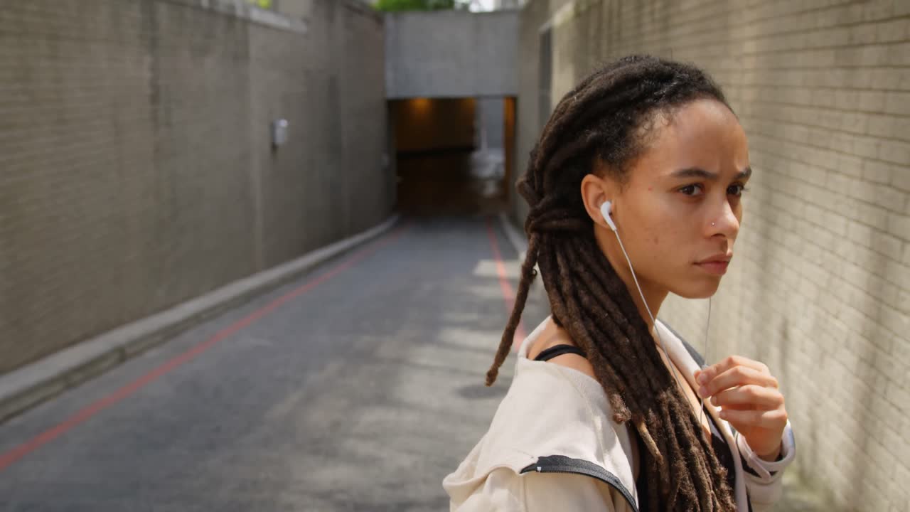 vista lateral de una joven mujer afroamericana con auriculares en la ciudad 4k