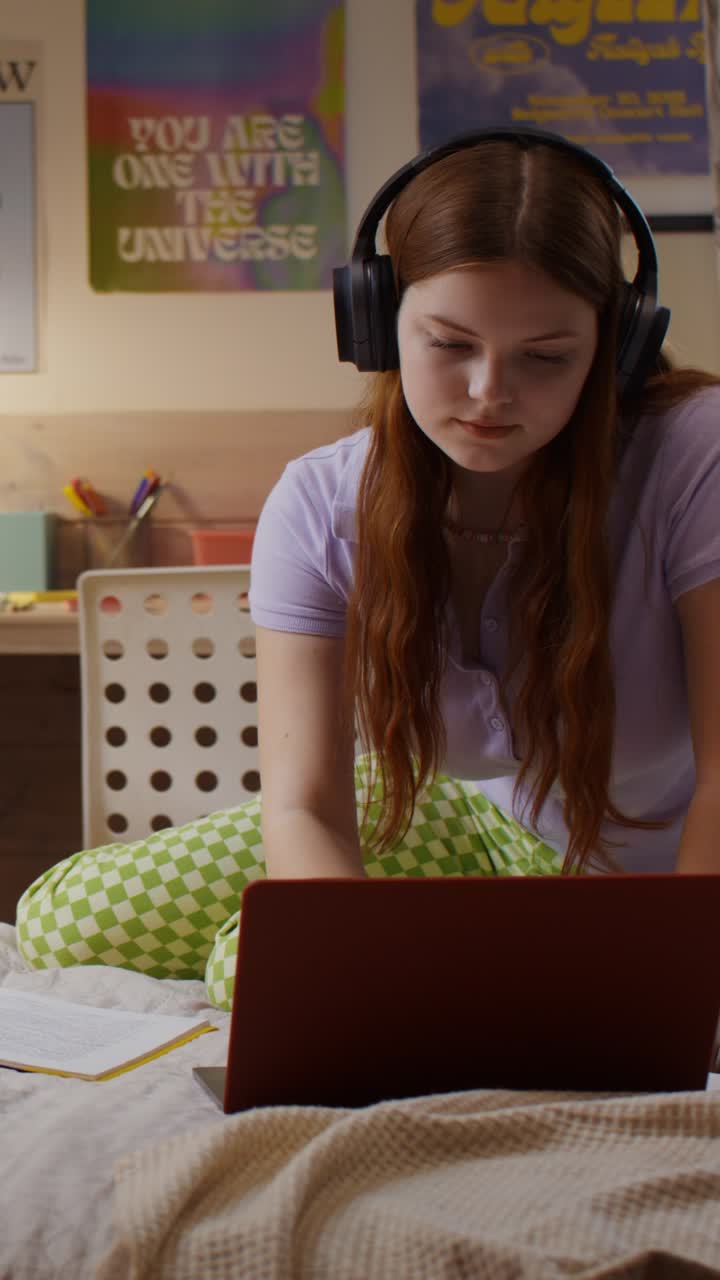 Teenage Girl Listening to Music and Studying on Laptop