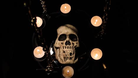 dummy human skull surrounded by candles on chains