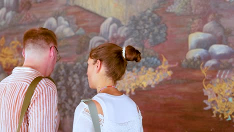 una pareja observa un intrincado mural en wat phra kaew