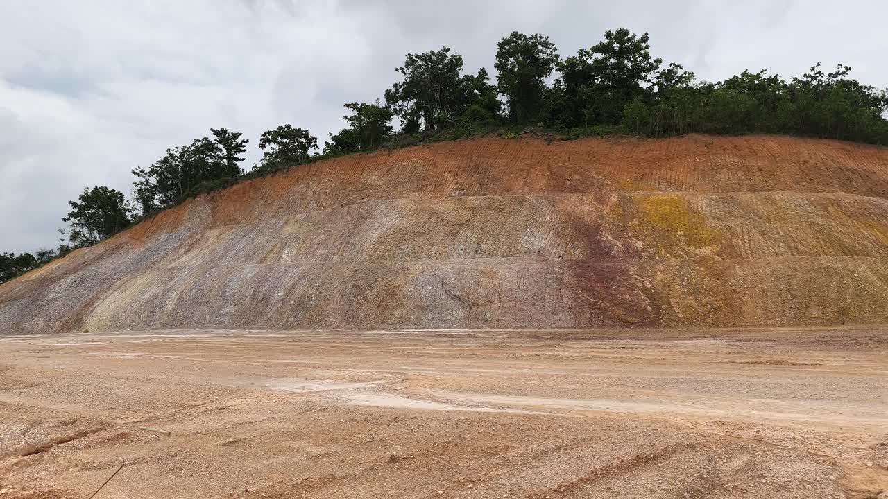 A cut hill and slope are exposed for infrastructure construction. The barren surface lacks protection, increasing the risk of erosion, danger, and potential landslides