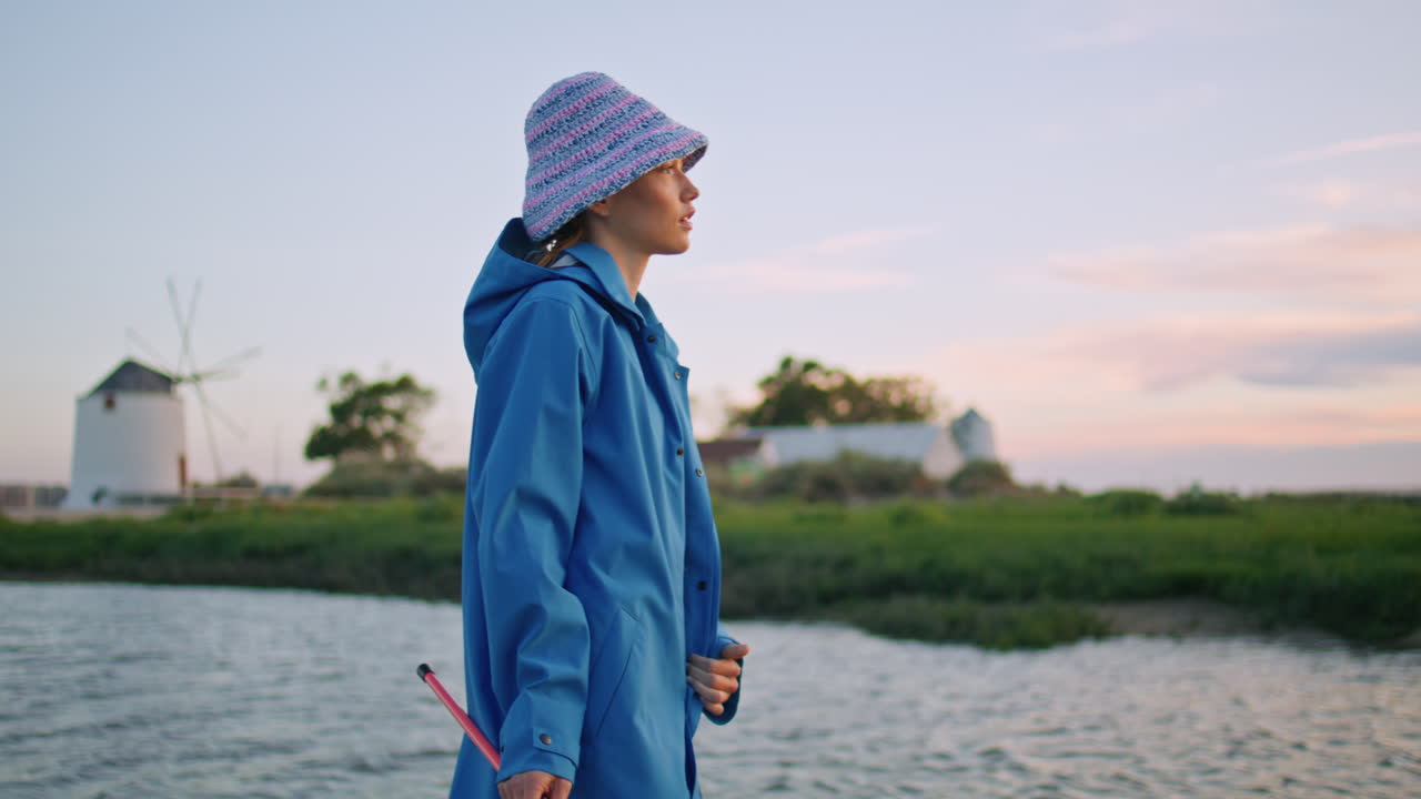 강에서 저녁을 즐기는 시 여자. 코트에서 카메라를 찾는 아름다운 여자