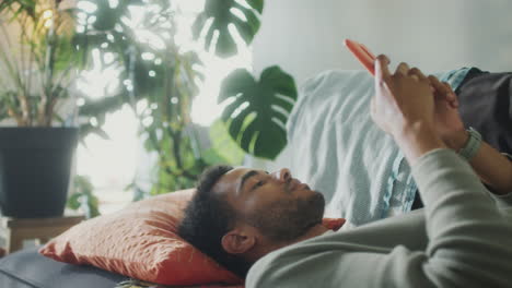 man lying on couch and texting on phone