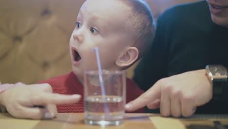 parents show child in red pullover glass with water straw