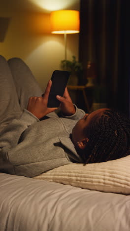 mujer usando un teléfono en la cama por la noche